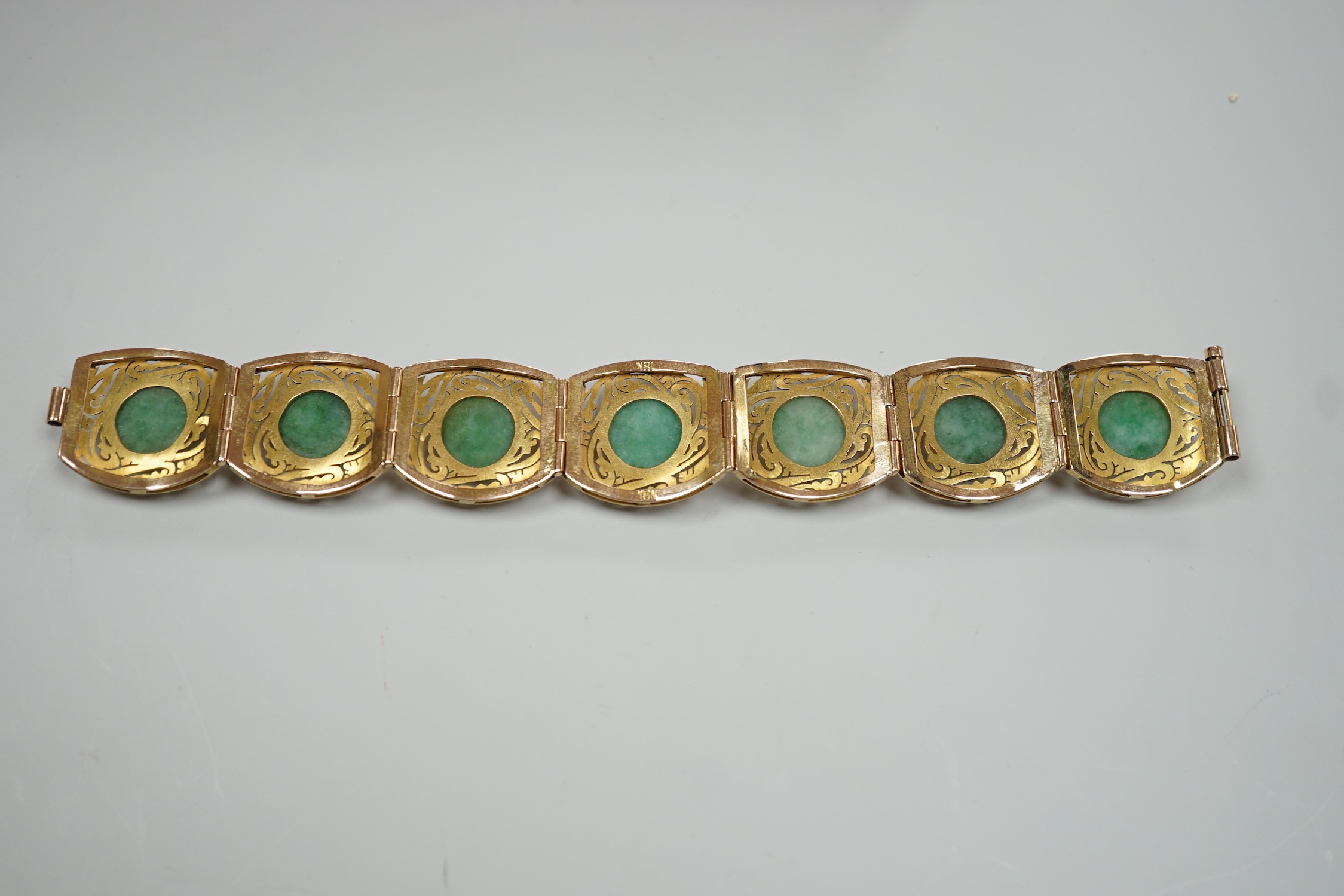 A continental 18k yellow metal and seven stone cabochon jade set bracelet, with pierced links, 18.5cm, gross weight 39.3 grams.